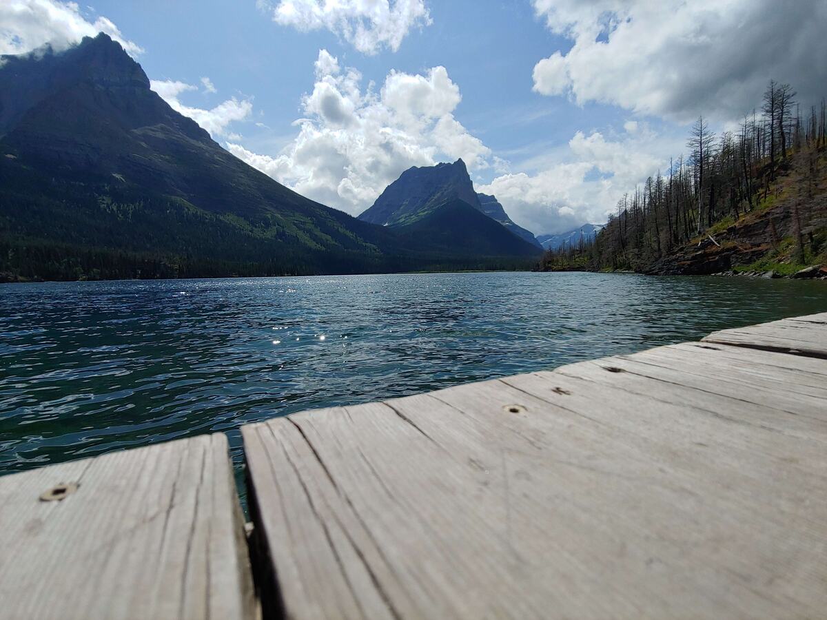 Mountain lake with a wooden dock in the foreground, Glacier National Park