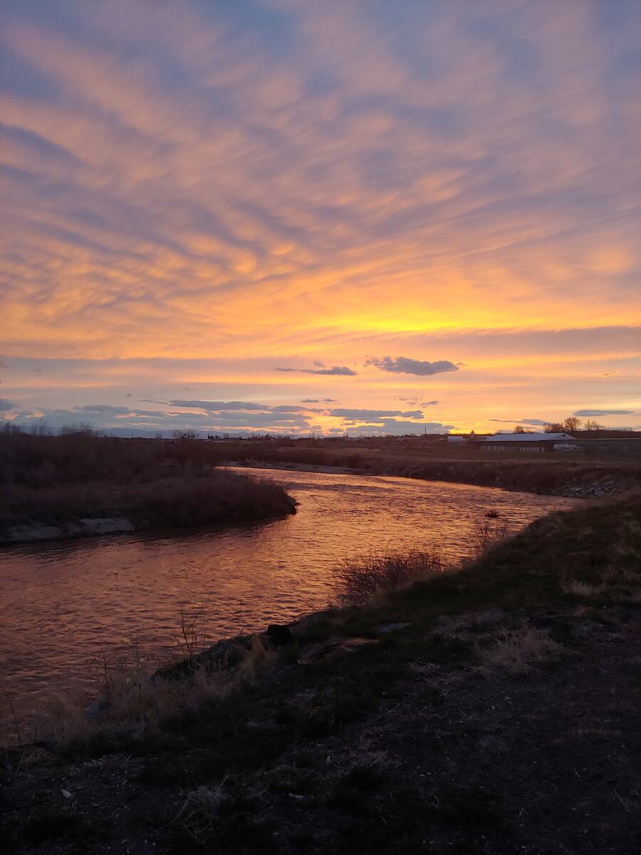 Vivid orange and purple clouds at sunset over a winding river