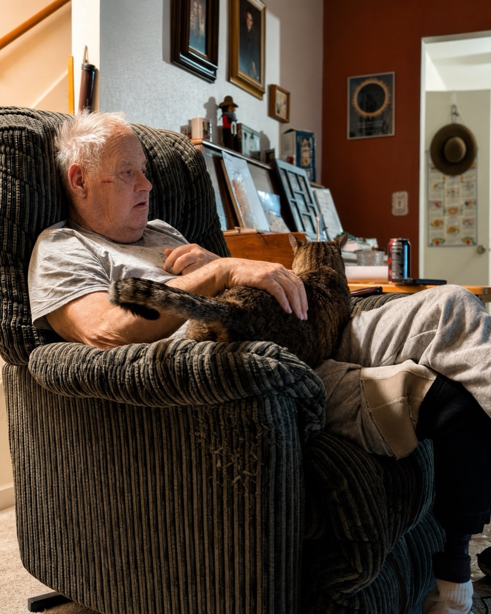 Mike reclined in his corduroy armchair with Goonhead stretched across his lap, one hand resting on the cat's back.