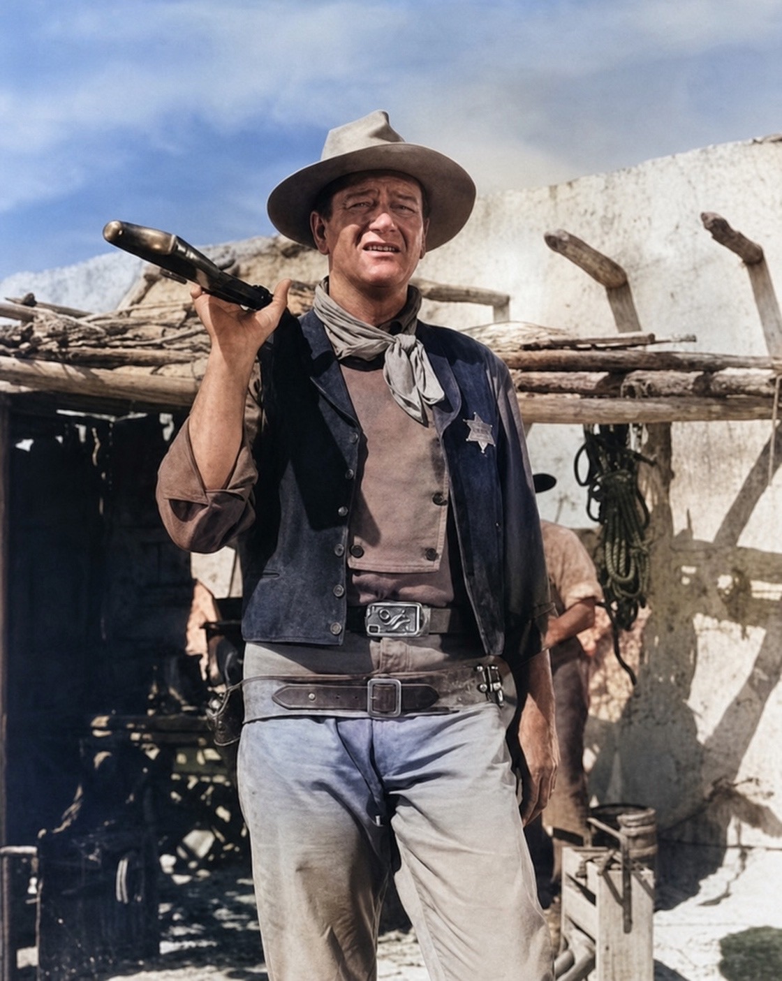 John Wayne as a sheriff, rifle over his shoulder, in a restored color still from a classic western.